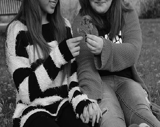 SHARING HAPPINESS. Sitting in the school yard, two female students exchanged flowers. They demonstrate that modern couples are not only bounded to heterosexual relationships.