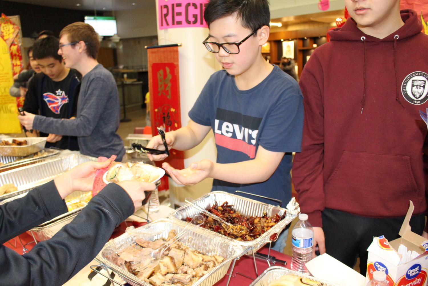 Nathen Li '20 serves a parent his mom's famous soy-braised pork.  On the side, he offered cabbage dumplings with spicy sauce.