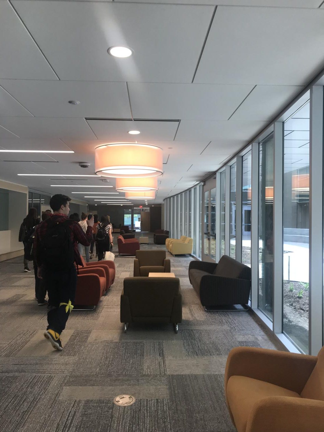 Larger hallways in the new addition are equipped with furniture for student seating between classes. The hallway looks out into the first school courtyard open for student use.