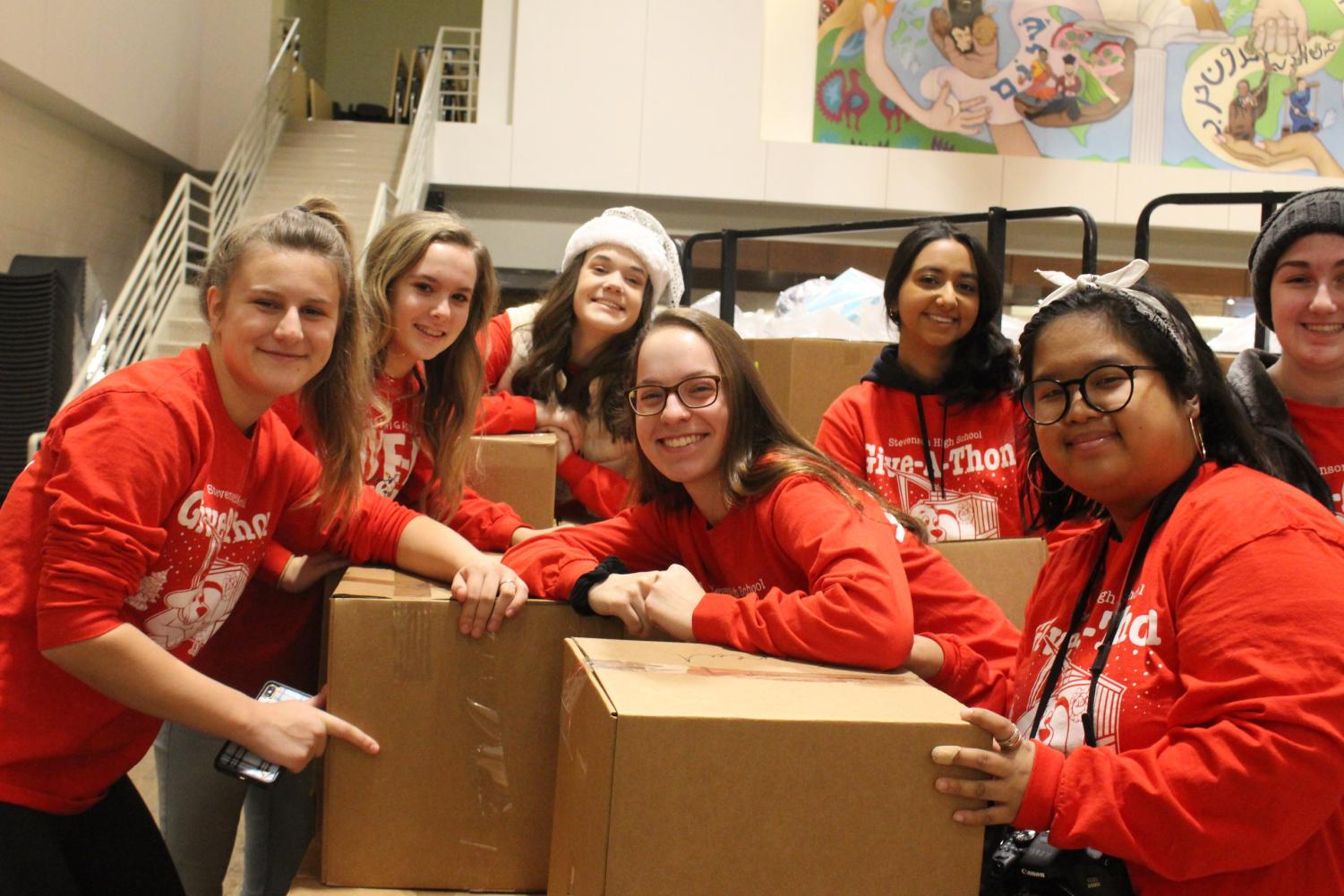 Students pose among food boxes before loading them onto a truck. Ninety-Five volunteers gathered in the Wood Commons to help deliver the gifts bought by many classroom leaders around the school.