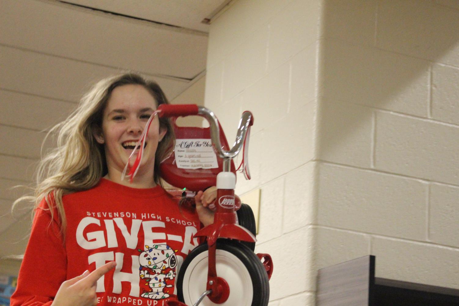 Nina Lozovnoy '20 carries a tricycle down the hall. Dozens of bikes lined the Wood Commons, ready to be delivered to the homes of the children that put the on their wishlist.