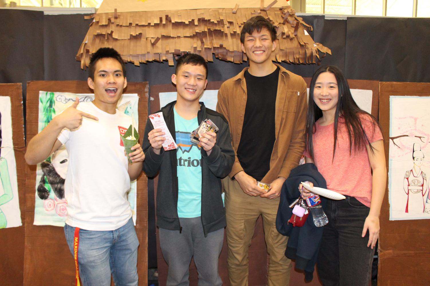 Patrick Tong '20, Connie Song '20, Gavin Meng '20 and Sean De Asis '20 smile in front of the art displays.