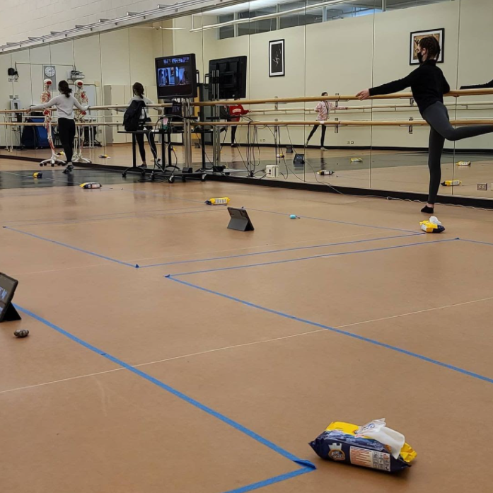 Several containers of wipes are strewn across the floor of a studio for a second period Dance 2 class preparing for their lesson. Students warm up while socially distanced with six foot restrictions taped to the ground to guide the, and reduce the risk of viral transmission. (Photo from Mr. Grice, Director of Fine Arts)