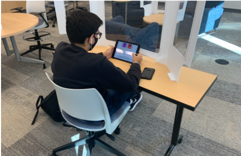 A Stevenson student works during his seventh period class while wearing a mask and being separated by a divider. The hybrid model has been a new experience for many students after nearly a year virtually. 