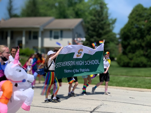 Students wearing rainbow clothing and inflatable costumes lift a Stevenson banner. Student Council, Sexuality and Gender Alliance (SAGA), Freshman Class Board and the Athletic Department organized Stevenson’s role in the parade.