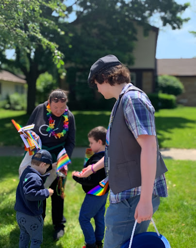Nathaniel Ramirez ’23 gives candy to Buffalo Grove residents. Students prepared pride flags and buckets of Tootsie Rolls to hand out to supporters who cheered on the parade.
