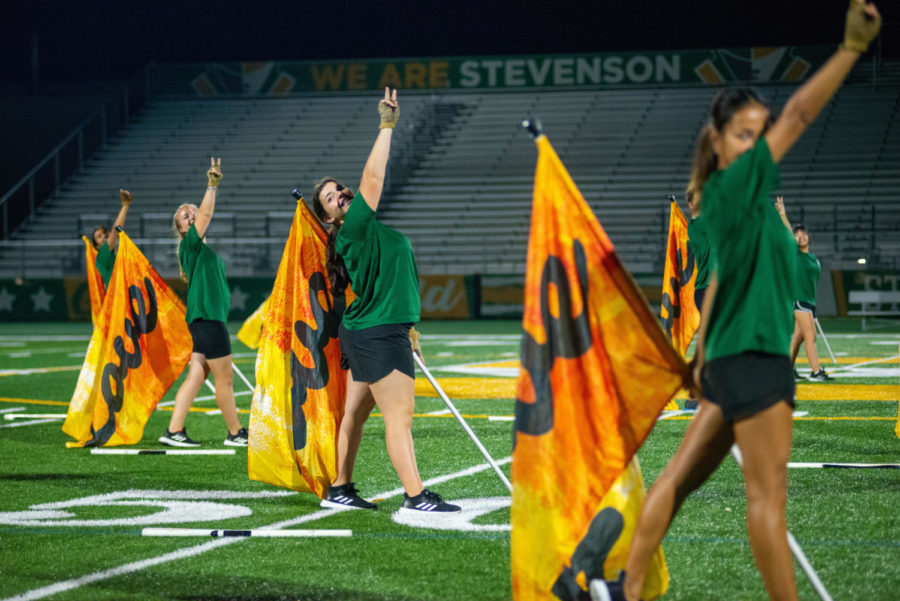 Colorguard performers wave yellow flags to the audience during their performance. Their choreography was prepared in advance for the closing assembly.