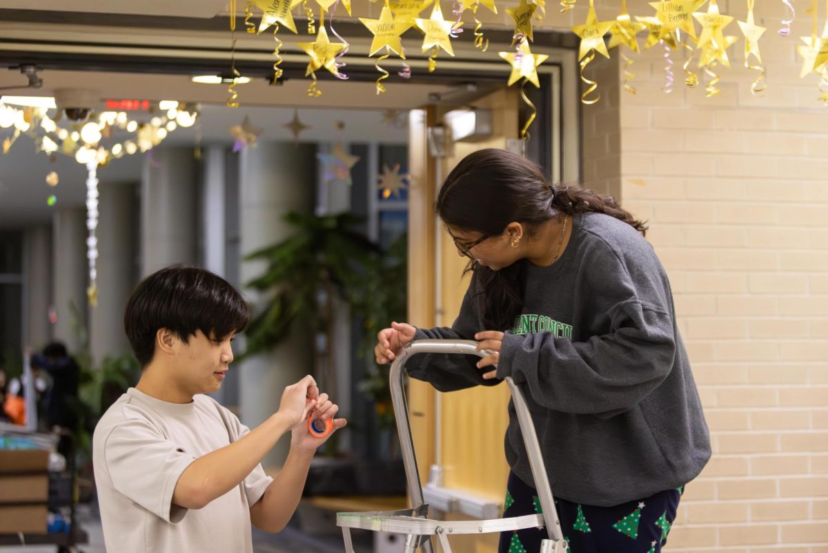 Caleb Song ’25 and Jennifer Johnson ’25 put up name hangers on the ceiling. Each class board creates an individual name hanger for students in their grade to spotlight each person.