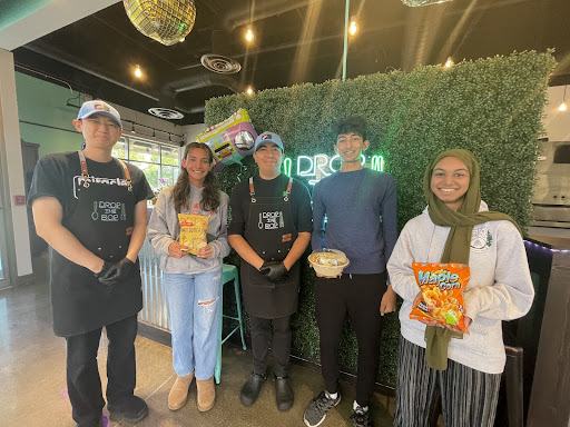 Staffers pose with the employees at Drop the Bop with traditional Korean chips. Being a new business, the employees were excited to promote their new restaurant, sharing their own culture.