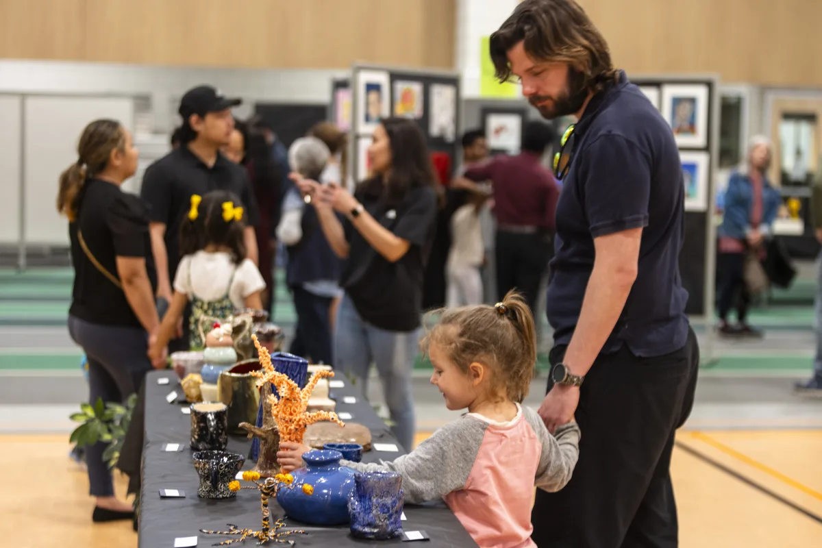 Families examine clay sculptures at Consortium ArtFest. Featuring work from artists across all twelve grades, Consortium encourages students to celebrate their artistic achievements with their family.