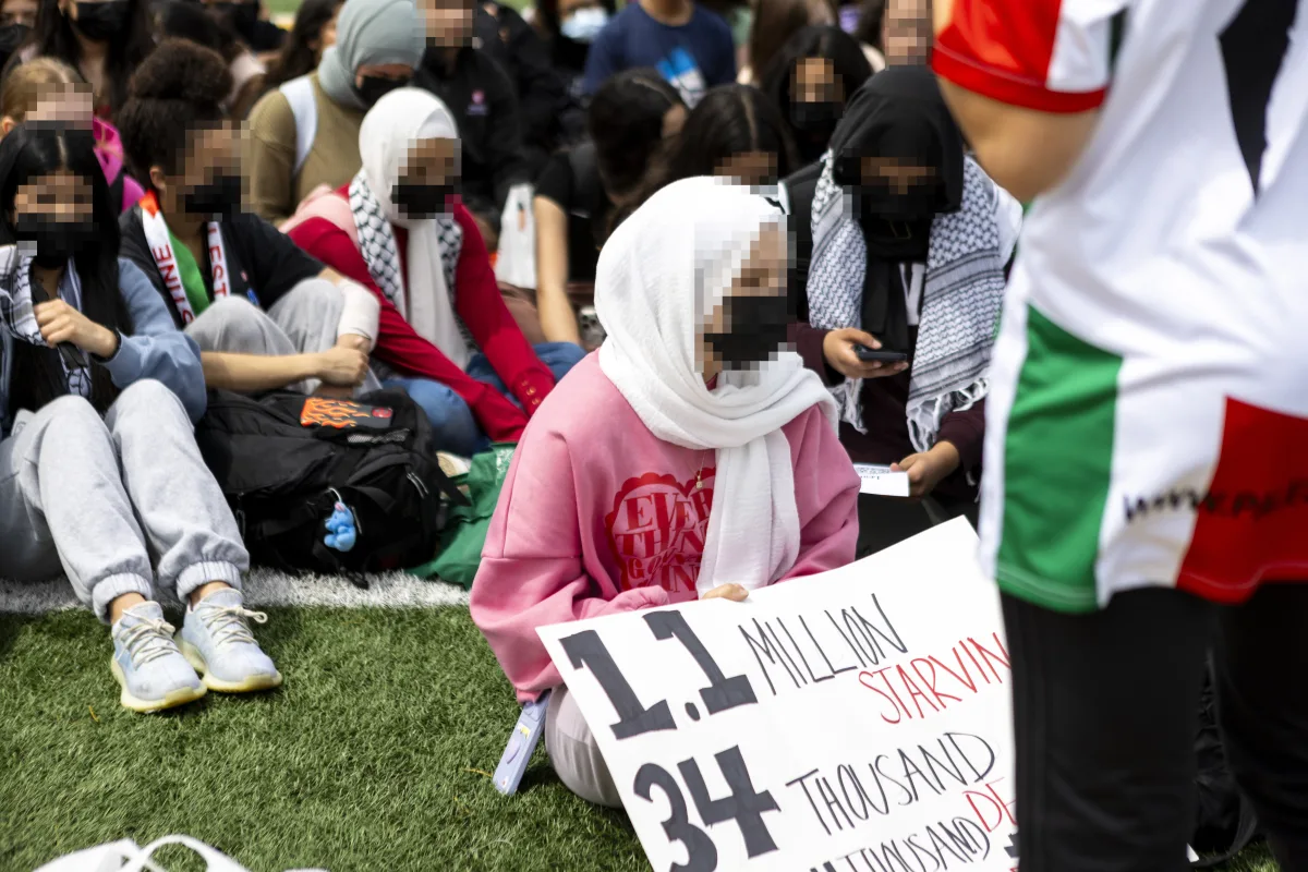 Students gather on the stadium turf as part of their walk-out. As a part of the walk-out, students brought posters and signage, but remained silent for the duration of the period following speeches.