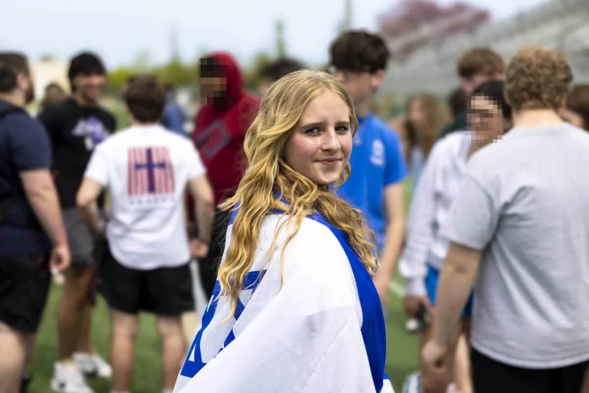 Protestor Eden Plotsky stands with the Israeli flag wrapped around her back, surrounded by fellow students. Students in support of Israel walked out as well, to represent their viewpoint.